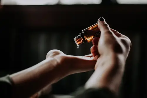 Individual pouring beard oil in the palm of their hands