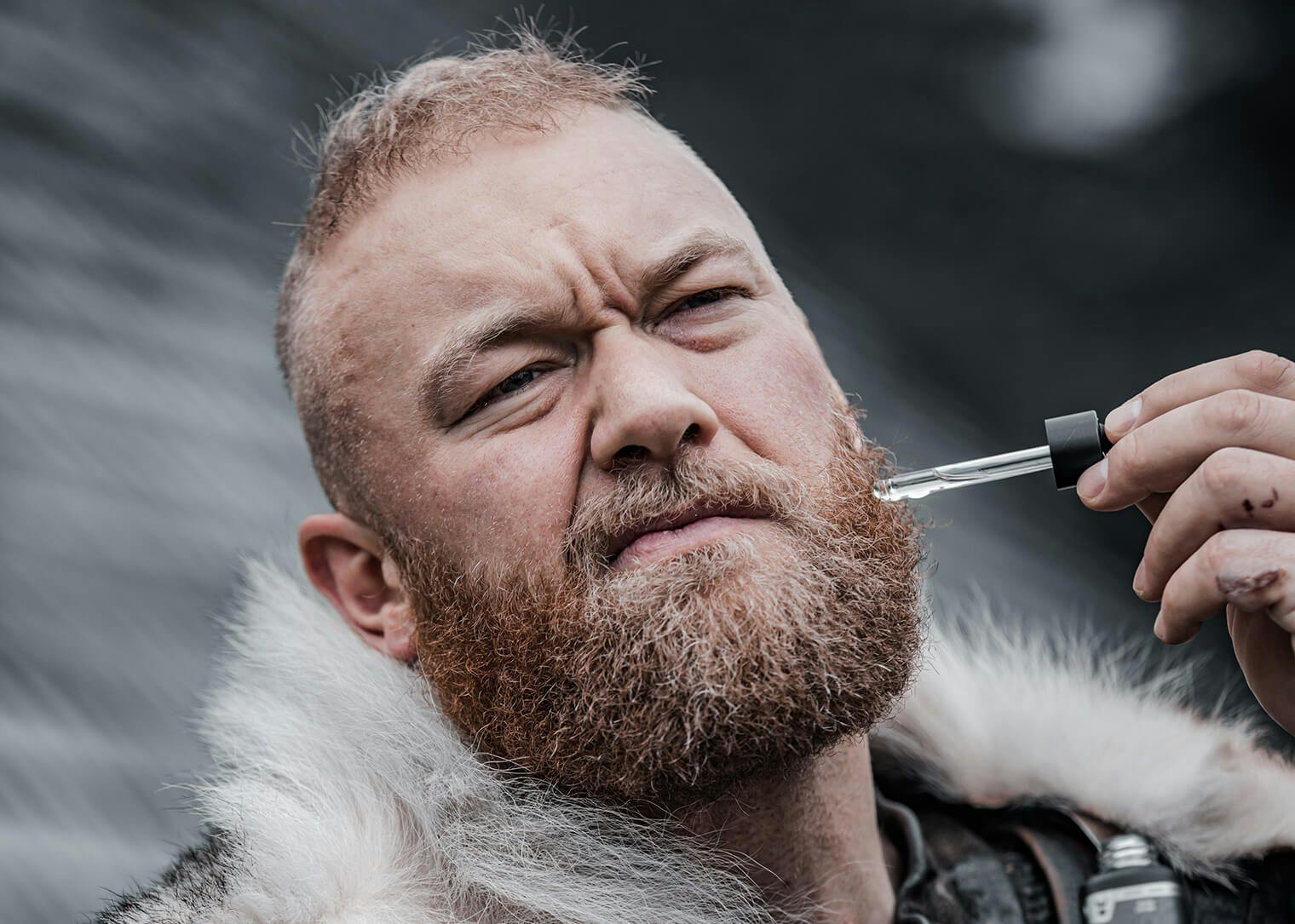 a viking man placing beard moisturizer on his beard