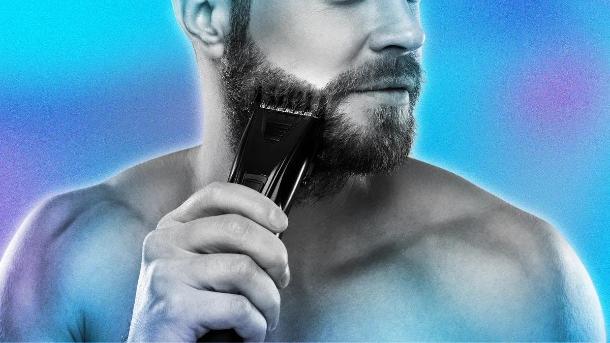 black man has shaving cream on his beard shaving it